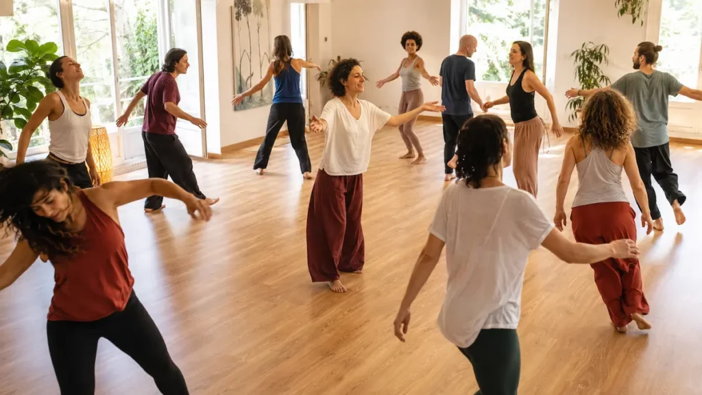 Groupe d’adultes participant à une séance de biodanza dans un studio lumineux, guidé par une facilitatrice.