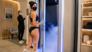 Femme prête à entrer dans une cabine de cryothérapie corps entier dans un centre spécialisé moderne.
